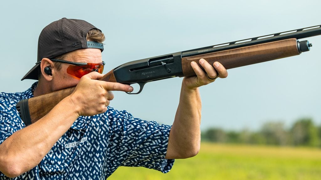 Shooter mounting the walnut Mossberg Maverick SA semi-auto shotgun at a clay target range